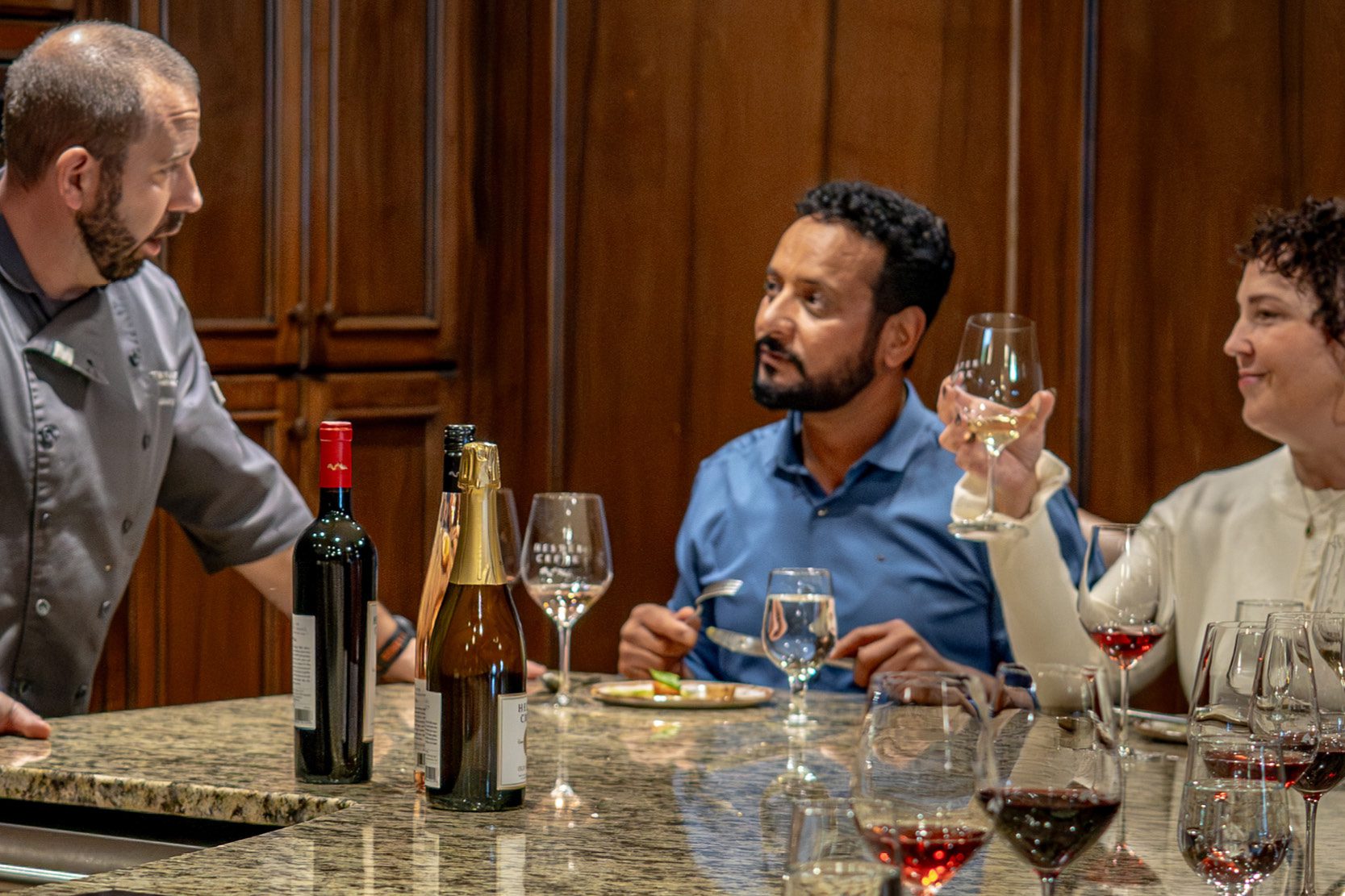 Chef talking to two people at a cooking class dinner